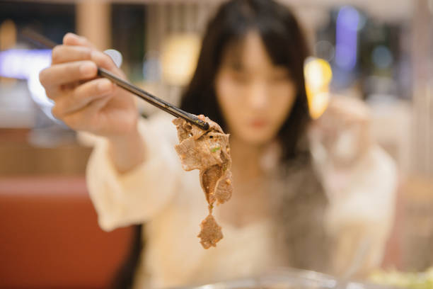 istock An Asian woman is eating beef hotpot at a restaurant, displaying cooked beef 2176647490