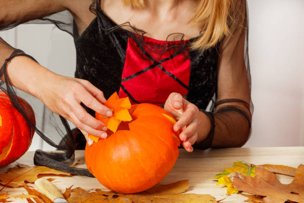 istock Hands carving a pumpkin surrounded by autumn leaves on table 2176655880