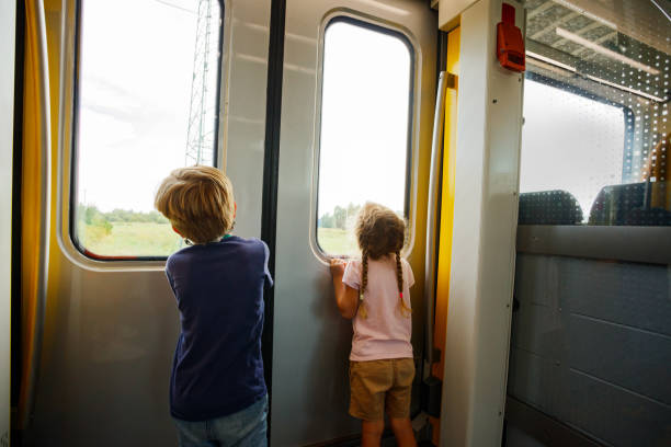 istock Two little children curiously look outside through a train door 2176656202