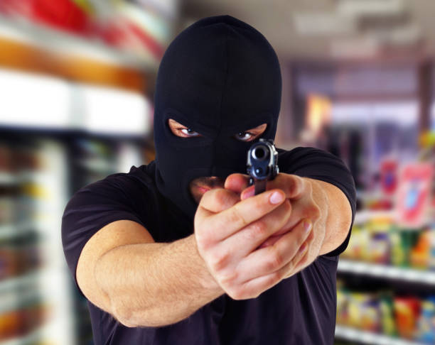 istock Masked criminal pointing gun in grocery store 2176663298