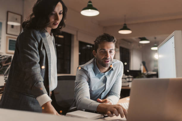 istock Two young businesspeople working late in an office together 2176663685