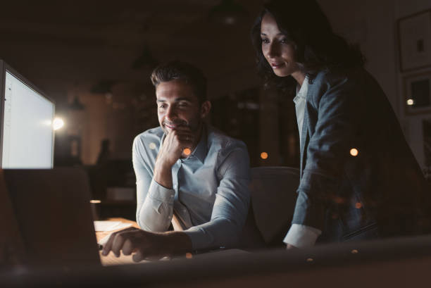 istock Two businesspeople working in a dark office at night 2176663937