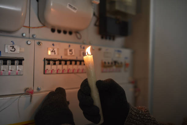 istock Checking the electricity power meter with a candle in cold winter days while there is power outage. 2176663986