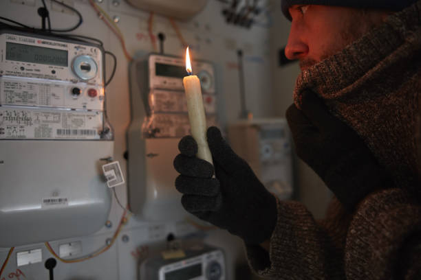 istock Checking the electricity power meter with a candle in cold winter days while there is power outage. 2176664002