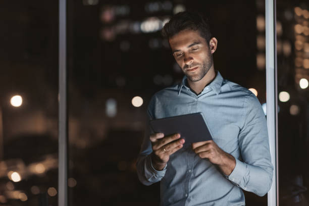 istock Young businessman using a tablet in his office at night 2176664026