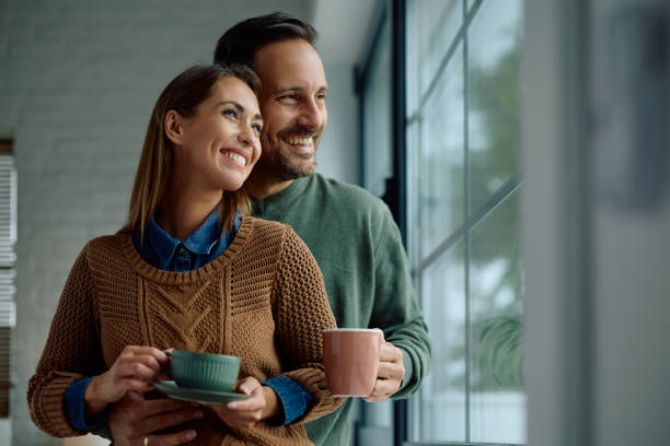 istock Happy couple drinking coffee by the window and looking through it. 2176666298