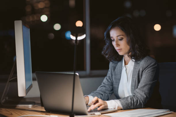 istock Young businesswoman using a laptop in her office at night 2176666882