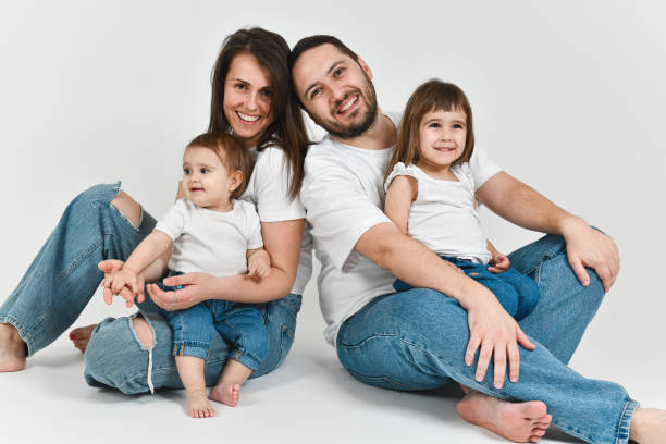 istock Cheerful Happy Family Looking at Camera While Sitting on Ground Hugging Their Two Daughters 2176667333