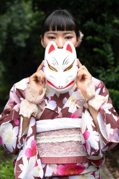 istock A woman in a kimono posing with a fox mask 2176673560