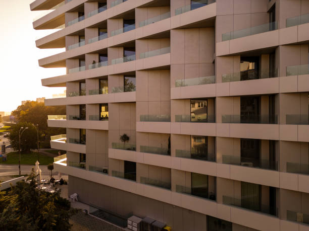 istock Modern high-rise building at sunset, featuring glass balconies and a tranquil urban setting. The golden hour lighting adds warmth to the minimalistic architecture. Shot with a drone 2176673719