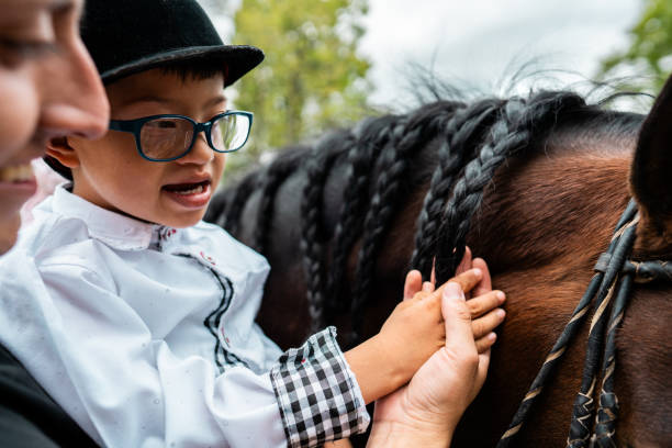Child boy with down syndrome petting horse outdoors