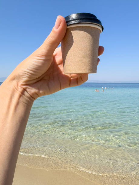 istock hand holds takeaway coffee cup over beautiful sea under blue sky with copy space 2176675969