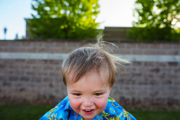 Portrait Of Little Boy Looking Through Fences In Playground