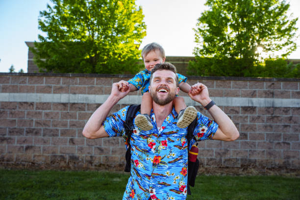 istock Young boy smiles while sitting on his dad's shoulders in the park 2176688239