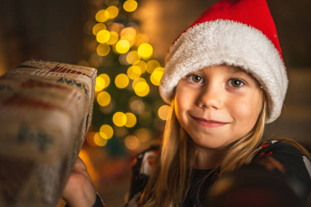 Self portrait of young girl child stand in front christmas tree and hold gift