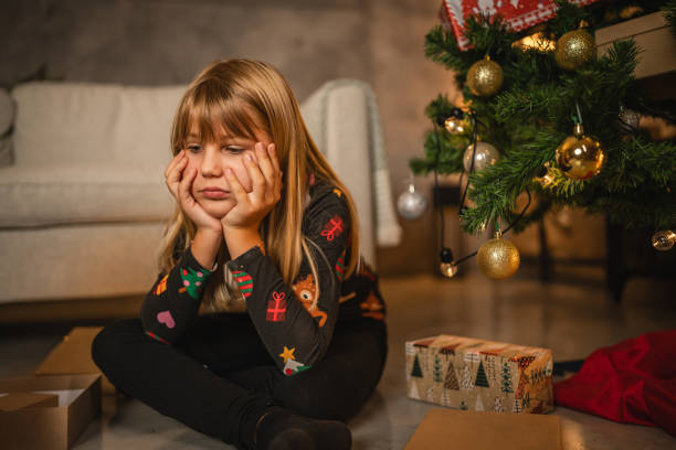 Young child girl sit with thoughtful, angry expression with gift box
