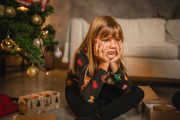 istock Young child girl sit with thoughtful, angry expression with gift box 2176689516