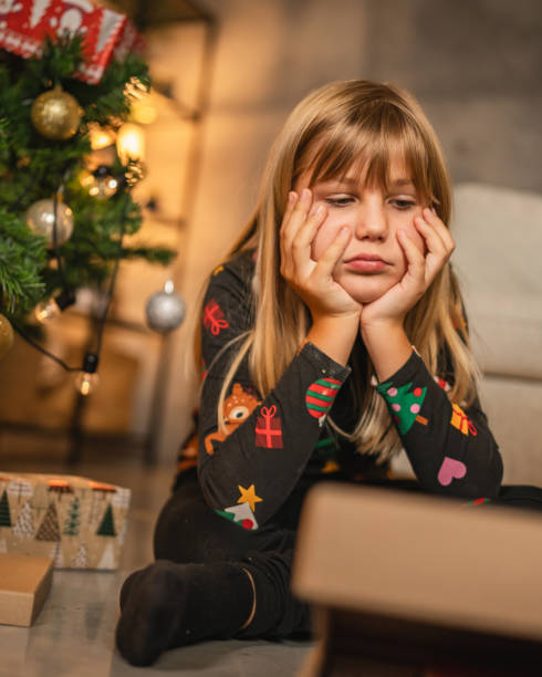 istock Young child girl sit with thoughtful, angry expression with gift box 2176689750