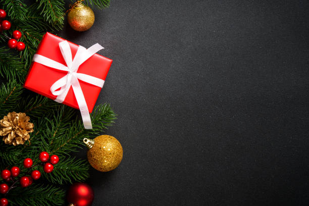 istock Christmas background with christmas tree, present box and holidays decorations at black. 2176692878