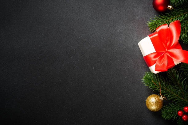 istock Black christmas flat lay background. Christmas tree with present box and holidays decorations at black. 2176692923