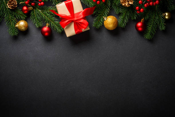 istock Black christmas flat lay background. Christmas tree with present box and holidays decorations at black. 2176692991