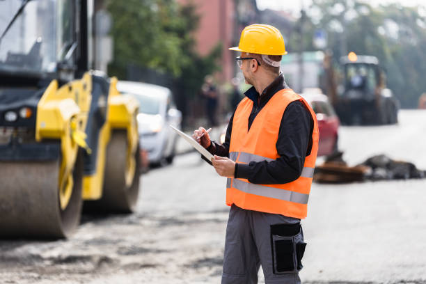 istock Construction worker inspecting roadwork during daylight, wearing safety gear on a busy urban street 2176695109