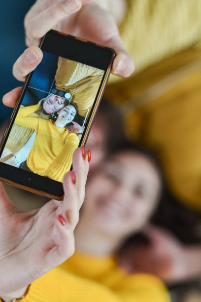 istock Beautiful Smiling Young Couple Taking Selfie on Mobile Device While Lying Head to Head 2176702178