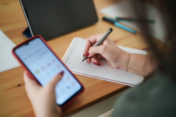 Young woman using mobile phone to calculate her home budget.