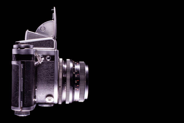 A side view of a classic vintage camera isolated on a black background showing its intricate design