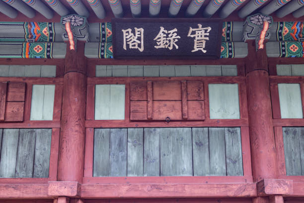 This photo showcases a close-up of the beautifully preserved wooden façade of Gyeonggijeon Shrine in Jeonju, South Korea. The image highlights the traditional Korean architecture, with intricately carved wooden pillars and beams painted in a rich, earthy red. The signboard at the top, featuring Chinese characters in elegant calligraphy, reflects the cultural and historical significance of the shrine. This sacred space honors the royal lineage and offers a glimpse into Korea’s vibrant heritage.