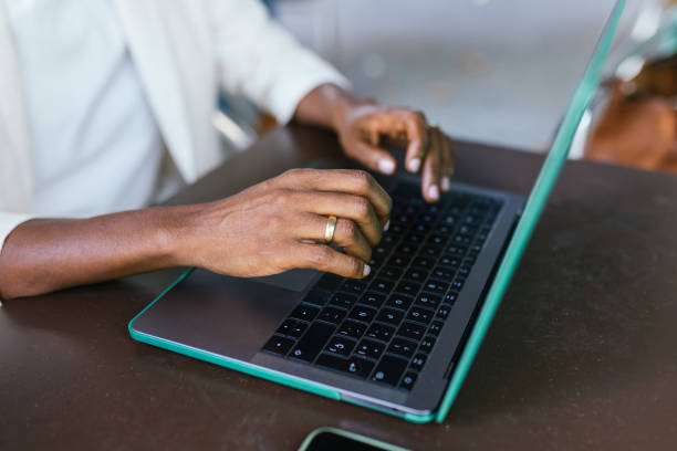 Focused Freelancer Typing on Teal Laptop in Bustling Coffee Shop
