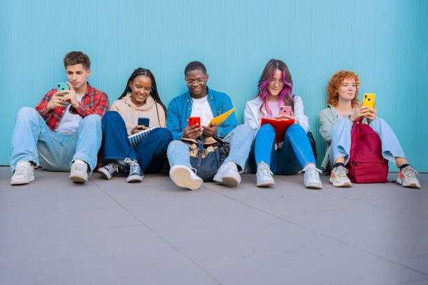 istock Diverse young people sitting outdoors using smartphones 2176715595