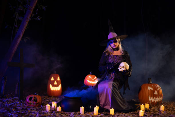 A charming  witch  with a carved pumpkin  and magic pot with smoke on Halloween night
