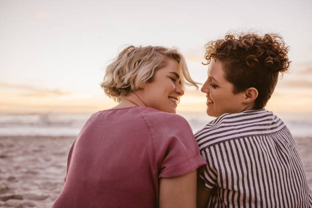 istock Smiling young lesbian couple enjoying a romantic beach sunset together 2176723367