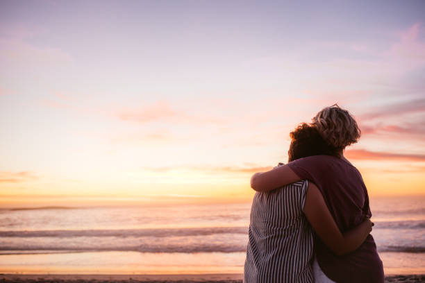 istock Affectionate lesbian couple watching the sunset by the ocean 2176723761
