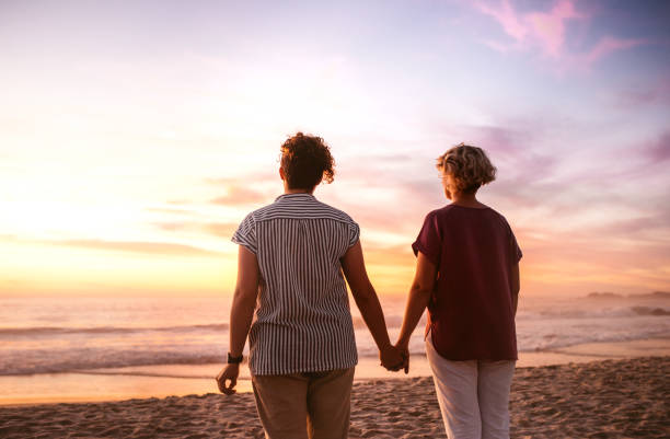 istock Affectionate lesbian couple holding hands watching a beach sunset 2176724196