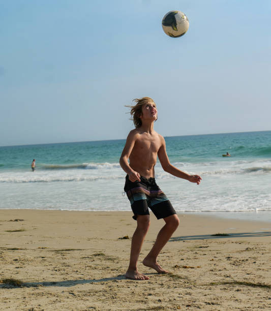 istock Young boy juggles a soccer ball on the Beach 2176724301
