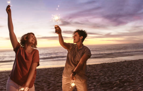 istock Laughing friends playing with sparklers at the beach during sunset 2176724392