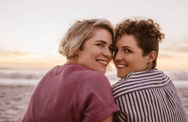 istock Smiling young lesbian couple watching a romantic beach sunset 2176724639