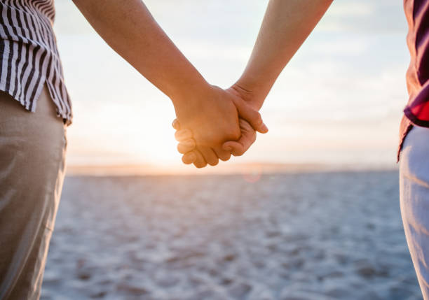istock Loving lesbian couple holding hands on a beach at sunset 2176724813