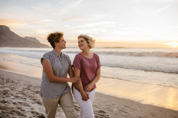 istock Smiling lesbian couple enjoying a romantic walk along a beach 2176724988