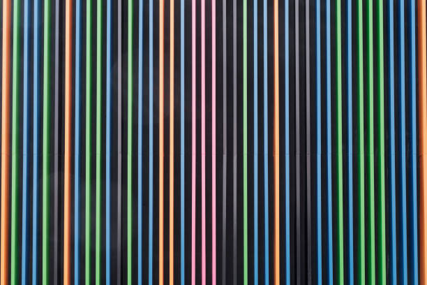 Symmetrical volume pattern of vertical colored stripes on dark background. Stripes alternate - blue, orange, green, and pink. Vibrant, colorful appearance. Design minimalistic, geometric, abstract