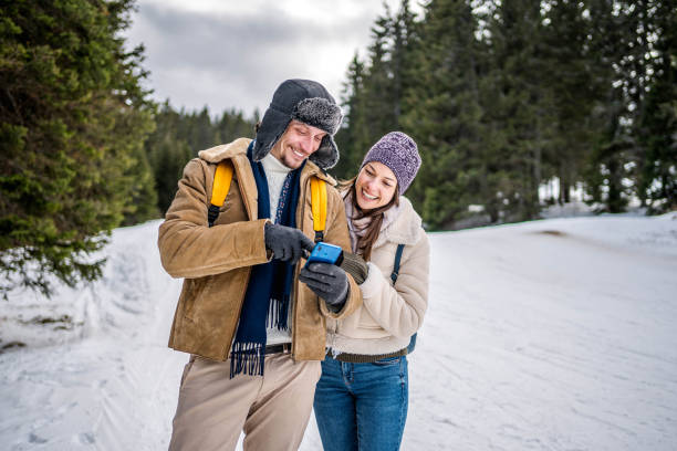 istock Cheerful couple using phone on a snowy mountain 2176735406