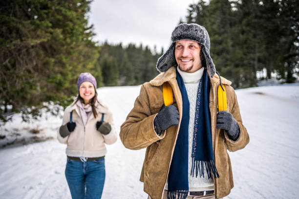 Young cheerful man enjoying while walking in the snow covered mountain