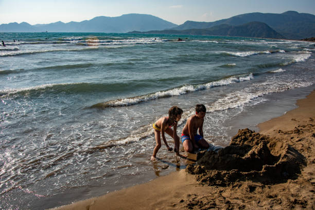 Siblings playing sand castle by the sea