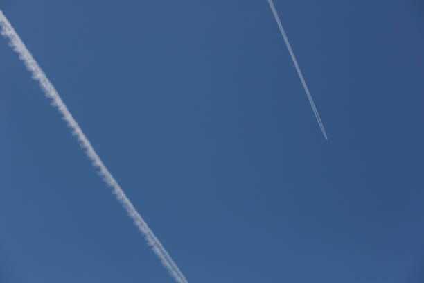 Two planes with their white trails in a blue sky
