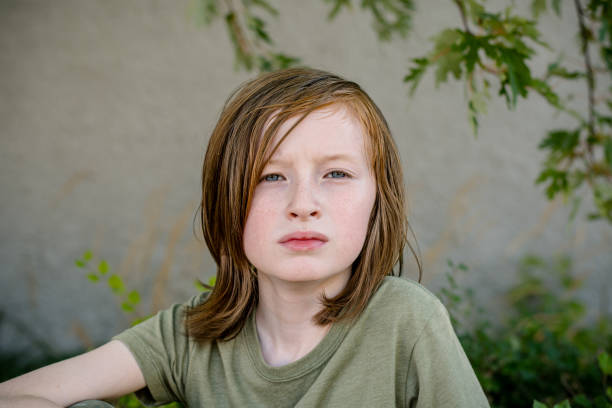 This striking portrait captures an 11-year-old non-binary autistic boy with freckles and long orange-brown hair, exuding a sense of calm and introspection, showcasing his unique identity