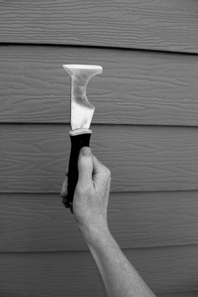 woman holding up putty knife paint scraper with hand against siding background