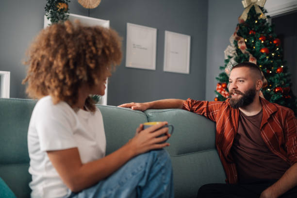 istock Couple relaxing on sofa drinking coffee and chatting at christmas 2176748863