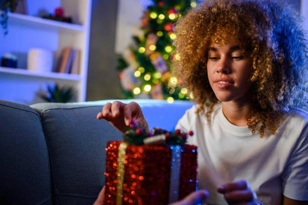 istock Woman opening christmas present by the tree 2176748953